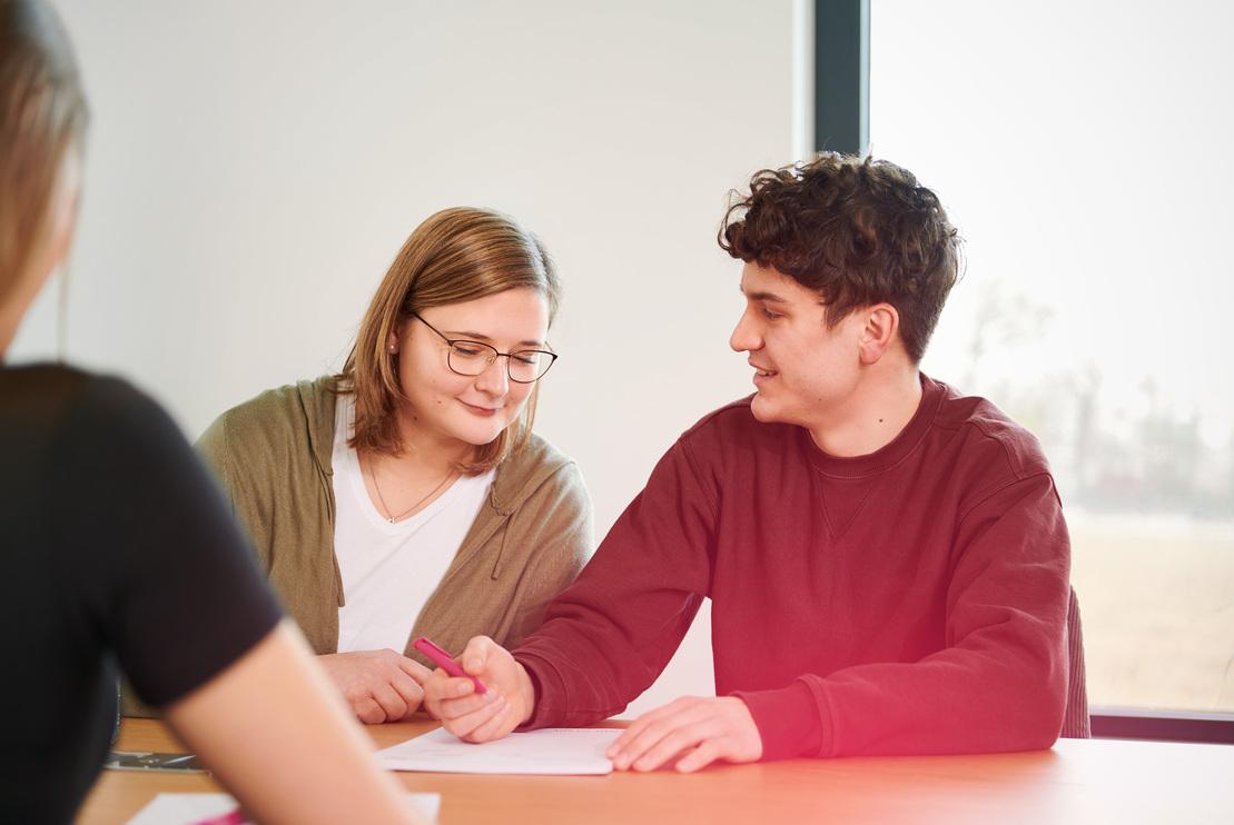 Eine junge Frau schaut einem jungen Mann über die Schulter Eine junge Frau schaut einem jungen Mann über die Schulter