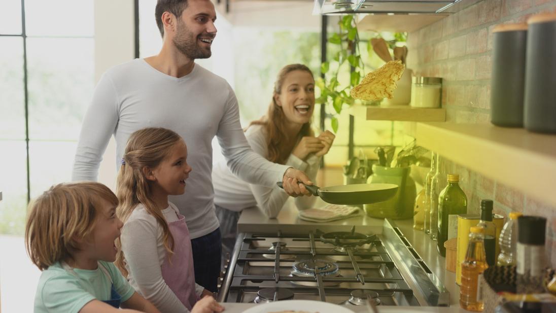 Eine Familie steht vor einem Gasherd und kocht Eine Familie steht vor einem Gasherd und kocht