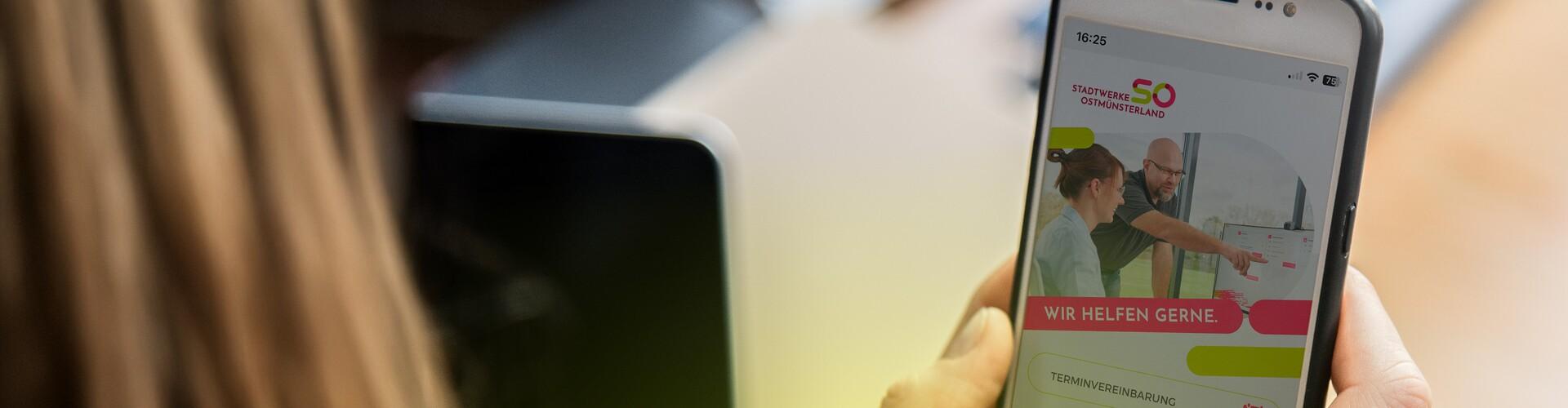 App Mein.SO Zwei Hände halten ein Smartphone mit der App Mein.SO auf dem Display