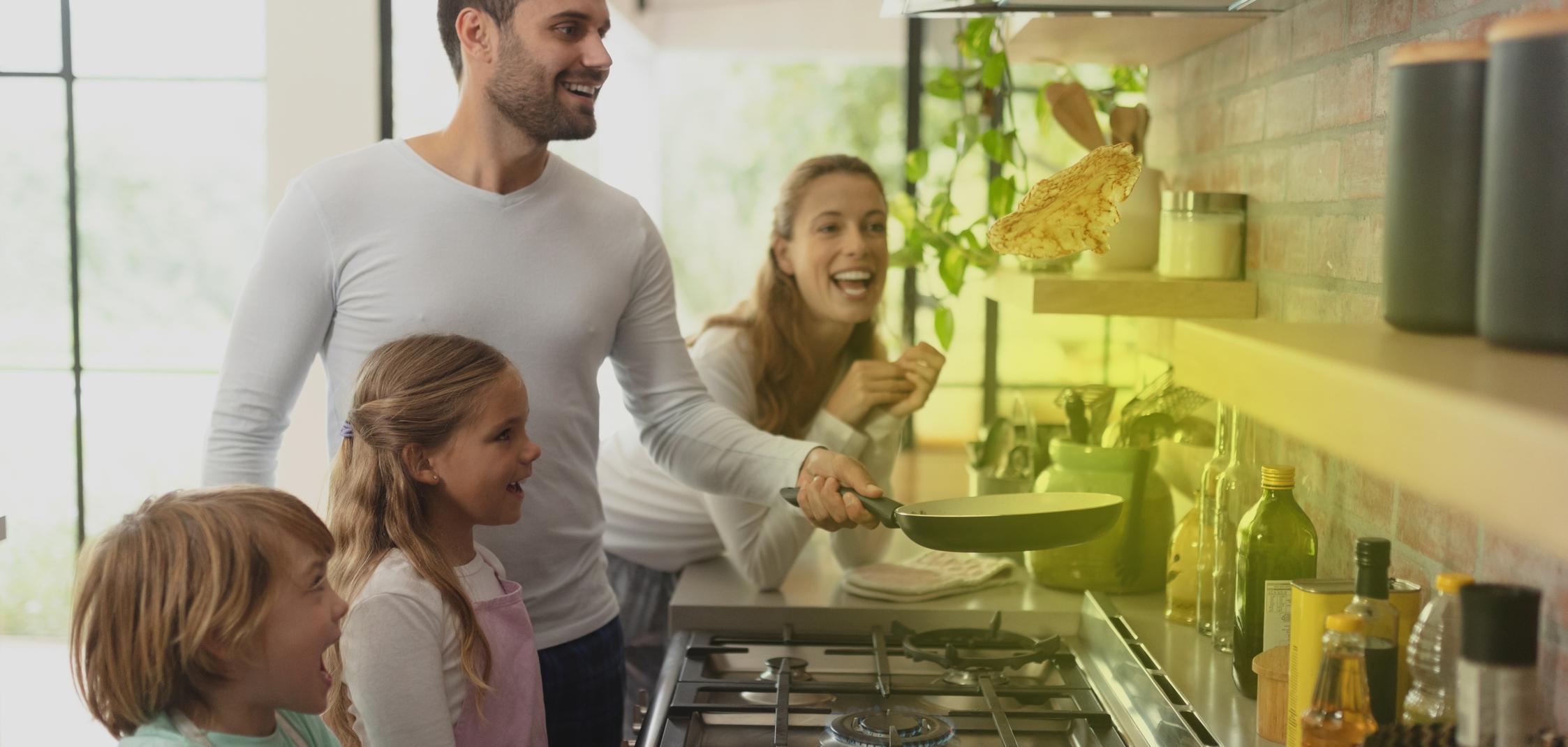 Eine Familie steht vor einem Gasherd und kocht Eine Familie steht vor einem Gasherd und kocht