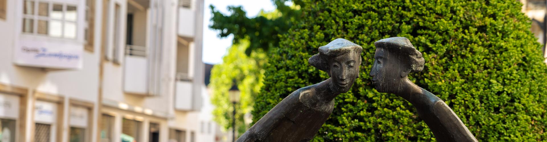 Eine Skulptur aus Bronze, die zwei Frauen zeigt, die sich etwas erzählen Eine Skulptur aus Bronze, die zwei Frauen zeigt, die sich etwas erzählen