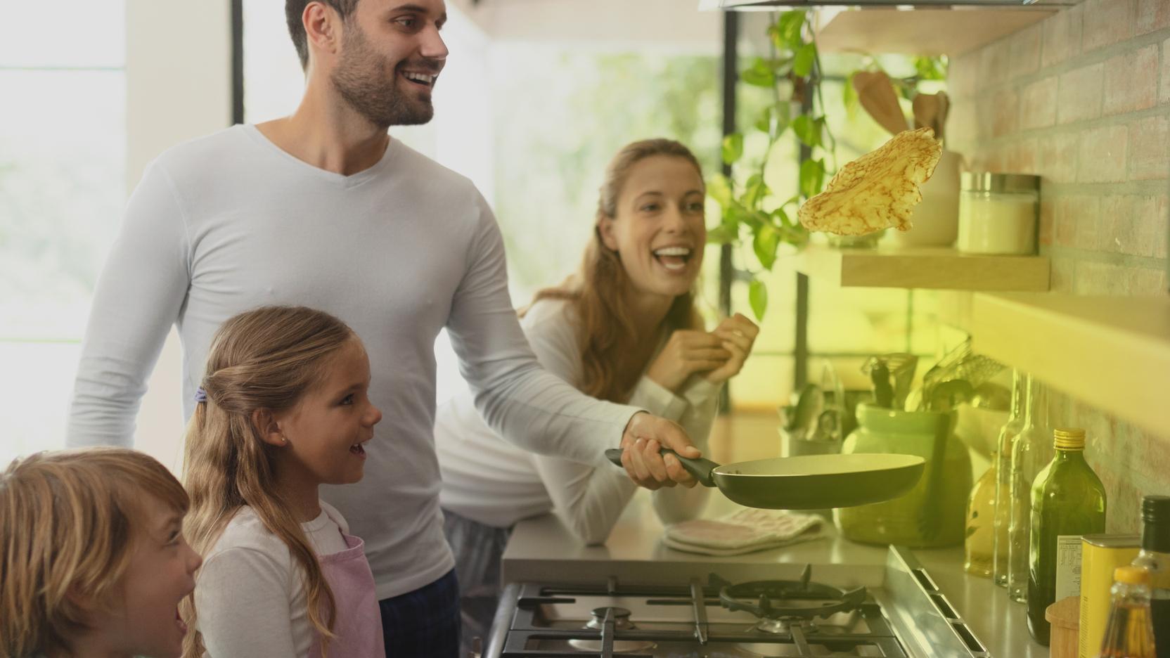 Eine Familie steht vor einem Gasherd und kocht Eine Familie steht vor einem Gasherd und kocht