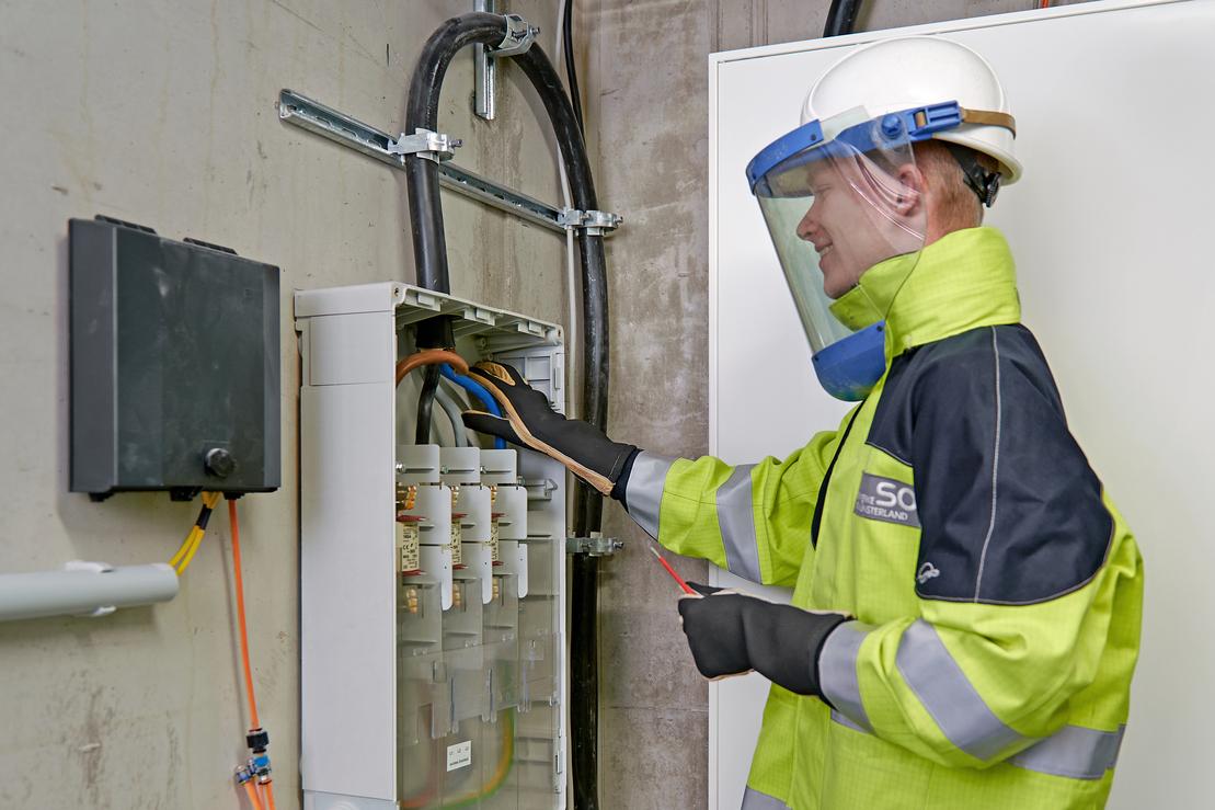 Ein Elektriker arbeitet in Schutzkleidung am Hausanschluss Ein Elektriker arbeitet in Schutzkleidung am Hausanschluss