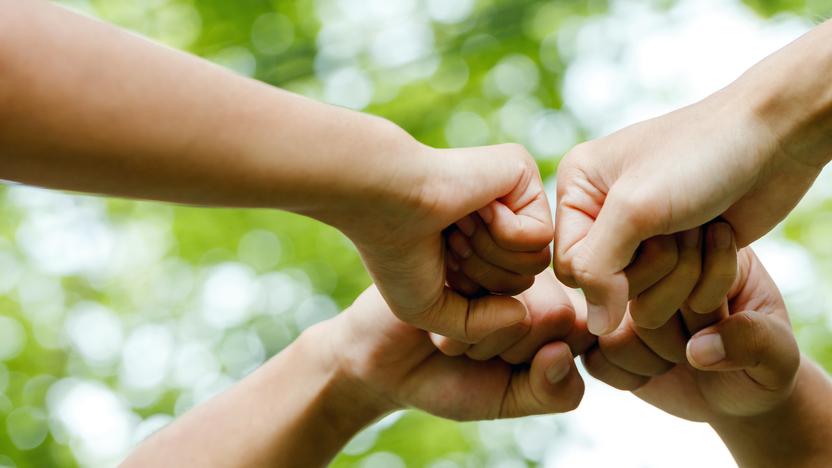 Vier Menschen recken gemeinsam die Fäuste.