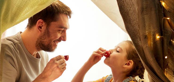 Ein Mann und ein Mädchen sitzen in einem Spielzelt Ein Mann und ein Mädchen sitzen in einem Spielzelt