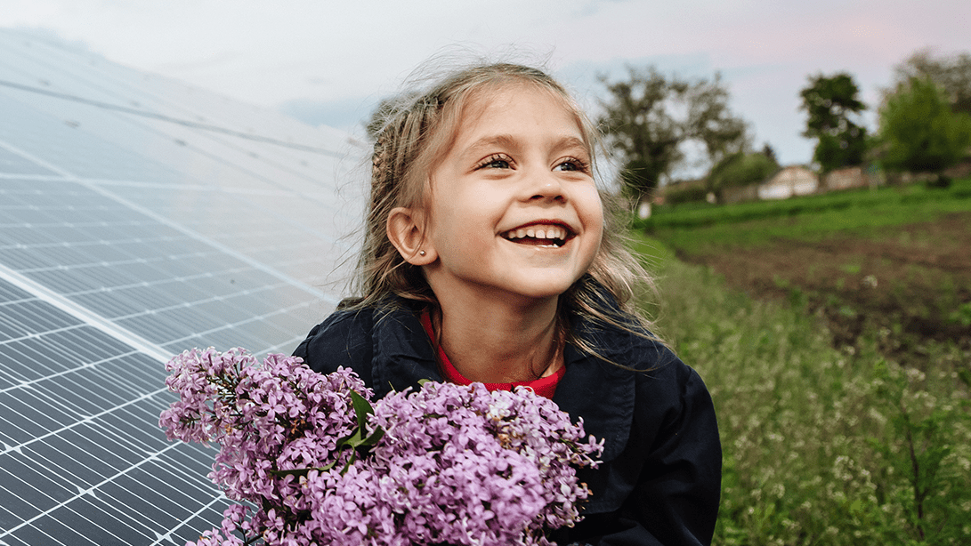 Ein Mädchen steht vor einem Solarpark mit mehreren PV-Modulen Ein Mädchen steht vor einem Solarpark mit mehreren PV-Modulen